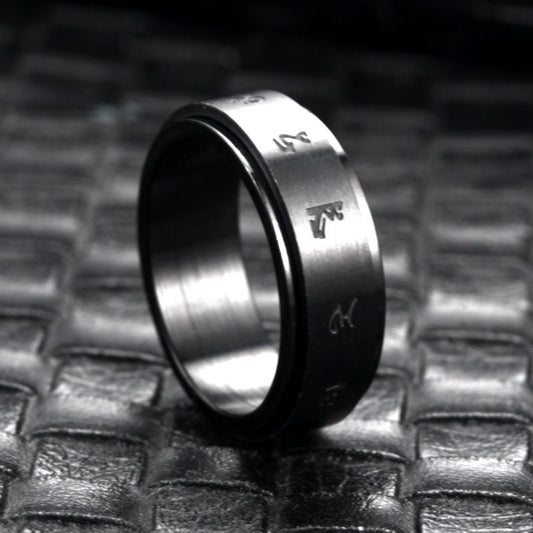 Matte black stainless steel ring with engraved minimalist symbols, displayed on a textured dark surface.