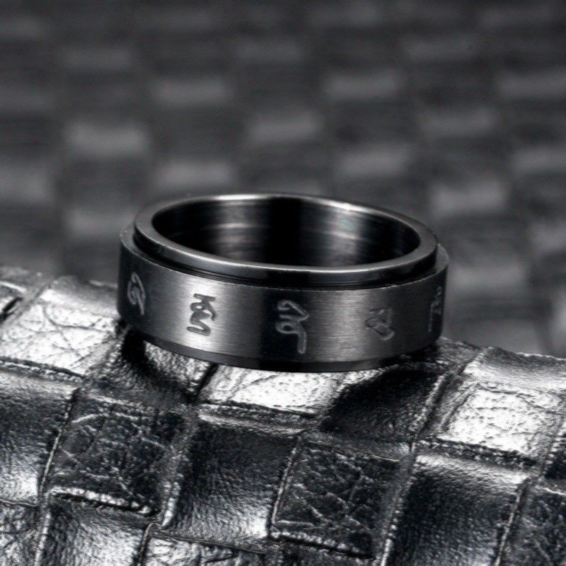 Black stainless steel ring standing upright on a dark textured surface, highlighting its shine and craftsmanship.