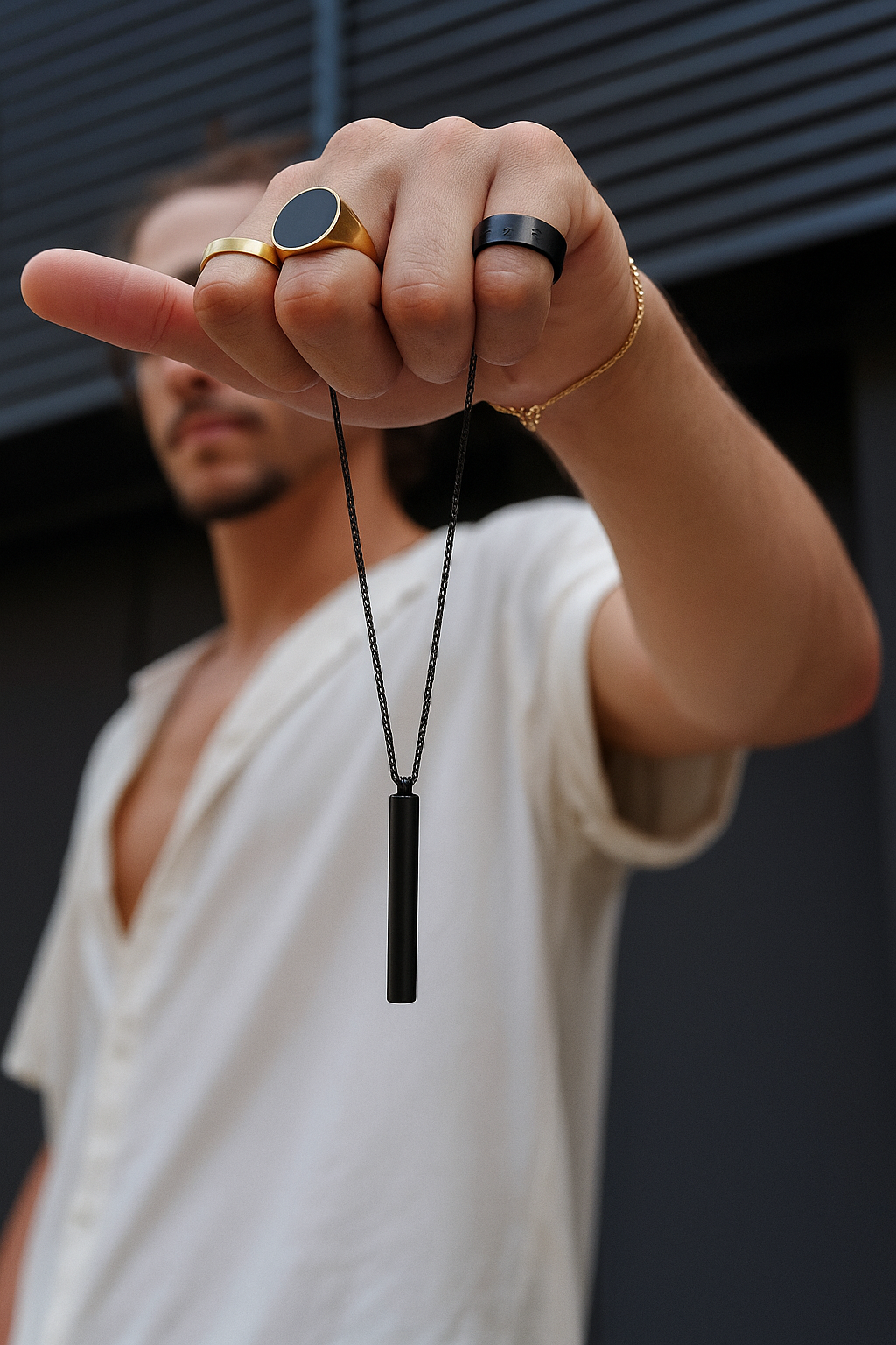 Man holding and wearing The Balance Chain pendant necklace, showing its elegant matte black finish and minimalist everyday style.