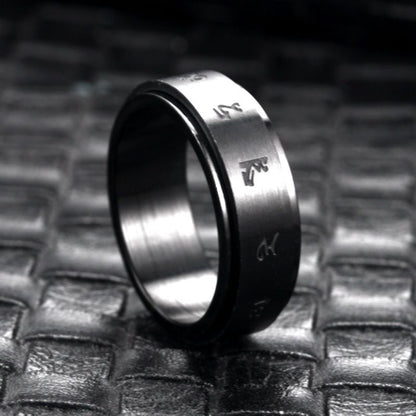 Matte black stainless steel ring with engraved minimalist symbols, displayed on a textured dark surface.