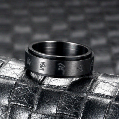 Black stainless steel ring standing upright on a dark textured surface, highlighting its shine and craftsmanship.